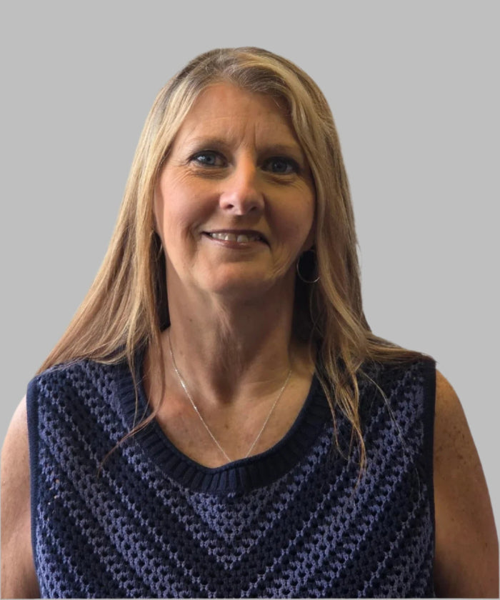 Woman wearing a blue patterned sleeveless top against a plain background