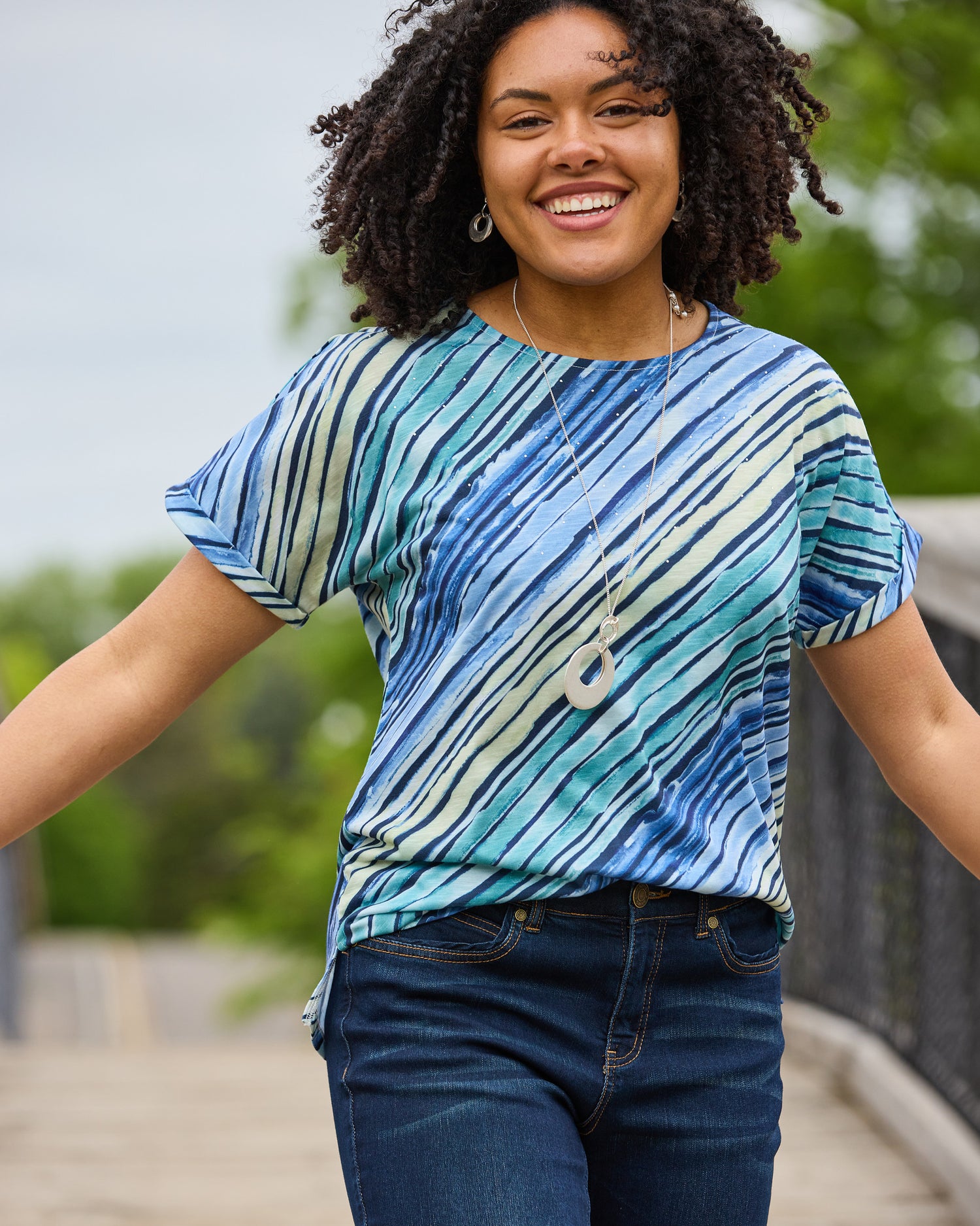 Explore our knit tops! Featuring a blue embellished watercolor stripe tee.