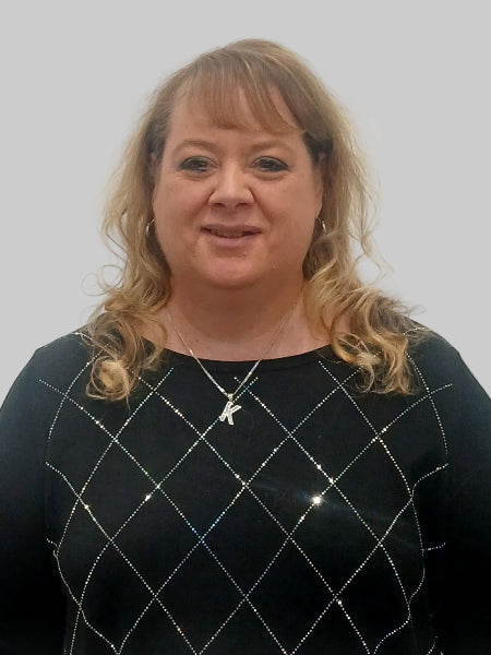 Woman wearing a black sweater with a diamond pattern against a plain background